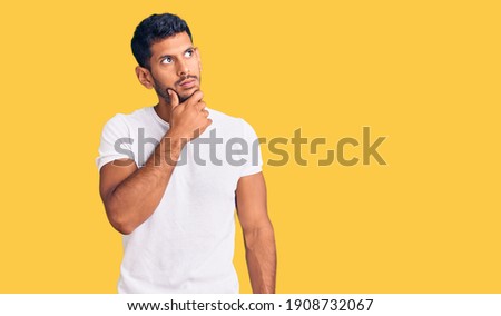 Young latin man wearing casual clothes with hand on chin thinking about question, pensive expression. smiling with thoughtful face. doubt concept. 
