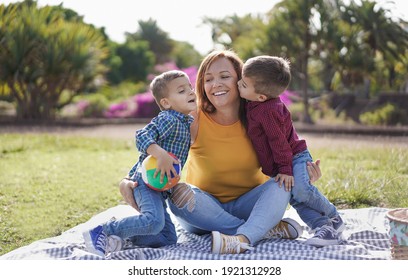 Young latin mother enjoy playful time with twin sons in nautre park with a pic nic