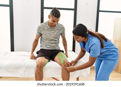 Young Latin Physioterapist Woman Make Knee Rehab Treatment To Hispanic Man At The Clinic.