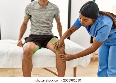 Young Latin Physioterapist Woman Make Knee Rehab Treatment To Hispanic Man At The Clinic.