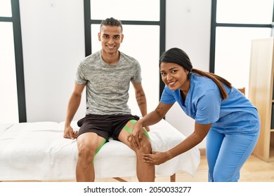 Young Latin Physioterapist Woman Make Knee Rehab Treatment To Hispanic Man At The Clinic.