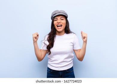 young latin pretty woman feeling happy, surprised and proud, shouting and celebrating success with a big smile against flat wall - Shutterstock ID 1627724023