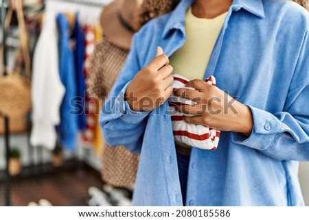 Young latin robber woman stealing handbag at clothing store.