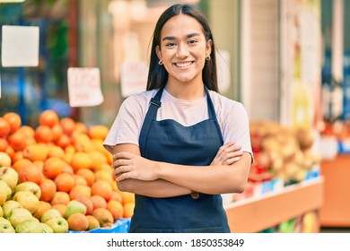 Young latin shopkeeper girl with arms crossed smiling happy at the fruit store. - Shutterstock ID 1850353849