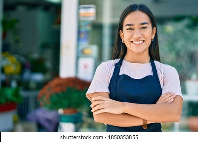 Young latin shopkeeper girl with arms crossed smiling happy standing at the florist