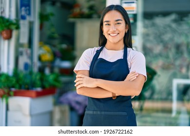 Young latin shopkeeper girl with arms crossed smiling happy standing at the florist - Shutterstock ID 1926722162