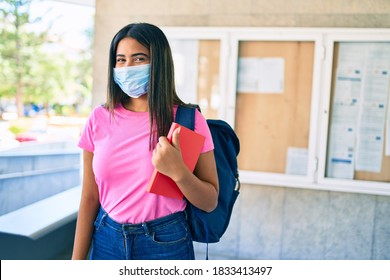 Young Latin Student Girl Wearing Medical Mask Holding Book At University Campus