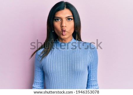 Young latin transsexual transgender woman wearing casual clothes making fish face with lips, crazy and comical gesture. funny expression. 