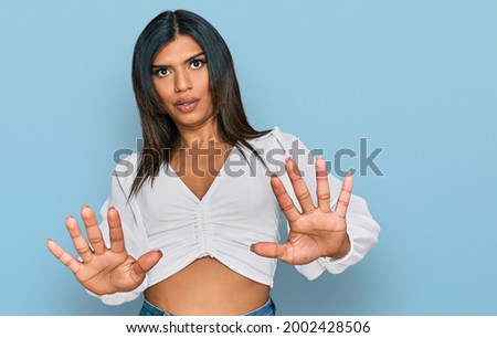 Young latin transsexual transgender woman wearing casual clothes doing stop gesture with hands palms, angry and frustration expression 