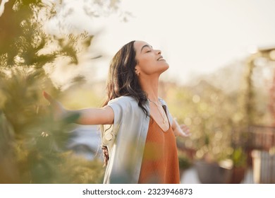 Young latin woman with arms outstretched breathing in fresh air during sunrise at the balcony. Girl enjoying nature while meditating during morning with open arms and closed eyes. Mindful woman relax. - Shutterstock ID 2323946873
