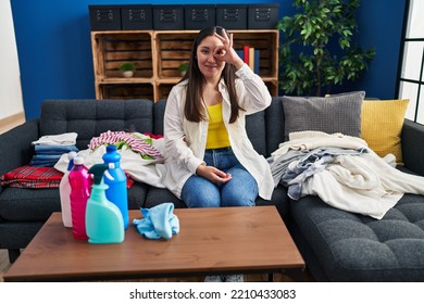 Young Latin Woman Doing Laundry At Home Smiling Happy Doing Ok Sign With Hand On Eye Looking Through Fingers 