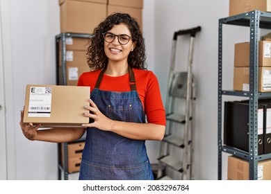 Young latin woman ecommerce business worker holding package at office