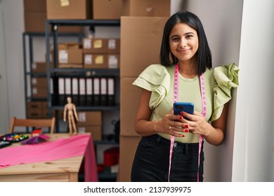 Young latin woman ecommerce business worker using smartphone at designer studio - Shutterstock ID 2137939975