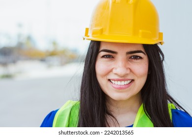 young latin woman engineer, wearing safety helmet and vest, worker of a construction site, standing on the street smiling looking at the camera, copy space, construction and industry concept. - Shutterstock ID 2242013565