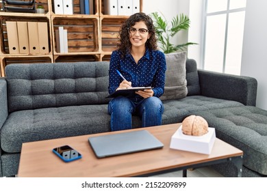 Young Latin Woman Having Psychology Session Writing On Clipboard At Psychology Center