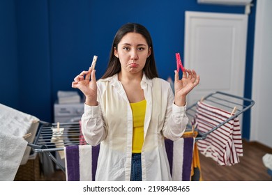 Young Latin Woman Holding Clothespins Hanging Clothes On Clothesline Depressed And Worry For Distress, Crying Angry And Afraid. Sad Expression. 