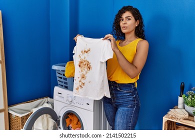 Young Latin Woman Holding Dirty T Shirt At Laundry Room