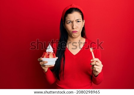 Young latin woman holding ice cream skeptic and nervous, frowning upset because of problem. negative person. 