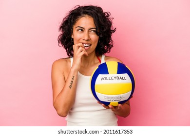 Young Latin Woman Holding A Volley Ball Isolated On Pink Background Biting Fingernails, Nervous And Very Anxious.