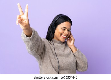 Young Latin Woman  Isolated On Purple Background Listening Music And Singing