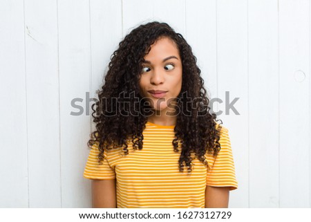 young latin woman looking goofy and funny with a silly cross-eyed expression, joking and fooling around