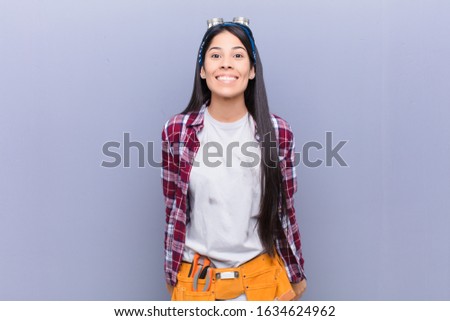 young latin woman looking happy and goofy with a broad, fun, loony smile and eyes wide open