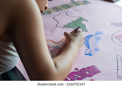 Young Latin Woman Making A Poster About The Colombian Amazon Region. Studying About The Culture And Richness Of The Prehispanic And Precolumbian Indian People. Drawing About The Amazonian Gastronomy.