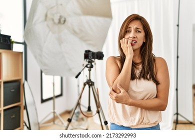 Young Latin Woman Standing At Photography Studio Looking Stressed And Nervous With Hands On Mouth Biting Nails. Anxiety Problem. 