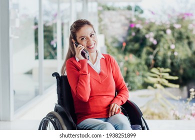 Young latin woman talking by phone in wheelchair at workplace in Mexico city - Powered by Shutterstock