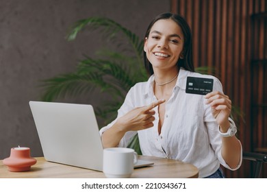 Young latin woman wear white shirt use laptop pc computer point on credit bank card shopping online order delivery sit alone at table in coffee shop cafe restaurant indoor Freelance business concept - Powered by Shutterstock