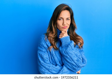 Young latin woman wearing casual winter sweater thinking concentrated about doubt with finger on chin and looking up wondering 