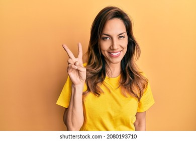 Young latin woman wearing casual clothes showing and pointing up with fingers number two while smiling confident and happy. 