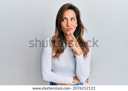 Young latin woman wearing casual clothes thinking concentrated about doubt with finger on chin and looking up wondering 