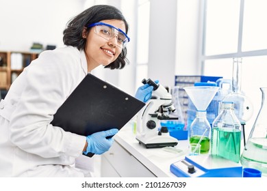 Young latin woman wearing scientist uniform using microscope at laboratory - Powered by Shutterstock