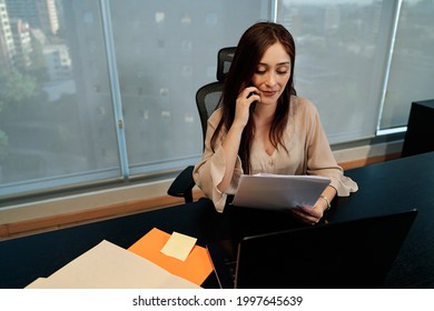 Young Latina Business Woman Talking On The Phone And Using Her Laptop To Work In The Office, Technology Concept