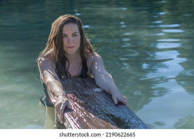 Young Latina Girl Holding On To A Wooden Board Bathing In A Lake