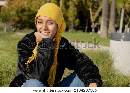 Young Latina survivor of cancer, with a scarf covering her head