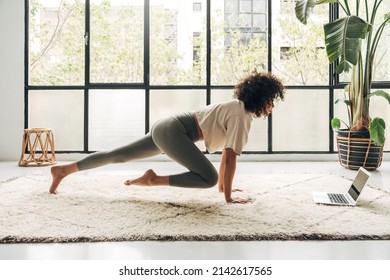 Young Latina Woman Exercising At Home Using Laptop To Follow Online Fitness Video Tutorial. Copy Space.