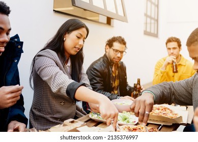 Young Latina woman grabbing food during a business lunch with a multiracial and diverse group of co-workers. after work. Friends food.