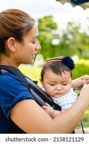 Young Latina Woman With Her Daughter In A Baby Carrier. Vertical Photo