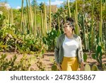 Young Latina woman looking around curiously among cacti. Taken in the Ethnobotanical Garden next to Santo Domingo in Oaxaca, Mexico.