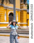 Young Latina woman smiling and enjoying her time exploring the vibrant streets of Barranco, Lima, Peru, on a sunny day.