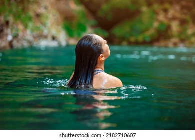 young Latina woman swimming in Rio Fortuna in Costa Rica with totally wet long hair. High quality photo