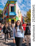 Young Latina woman walking in front of the brightly colored houses in Caminito, La Boca, Buenos Aires, enjoying the lively atmosphere.