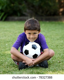 Young Latino Boy Sitting Ion Grass With Soccer Ball