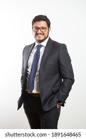 A Young Latino Businessman Wearing Glasses And Standing In A Dark Suit And Tie On A White Background