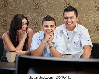 Young Latino Family Enjoying Television Indoors Together