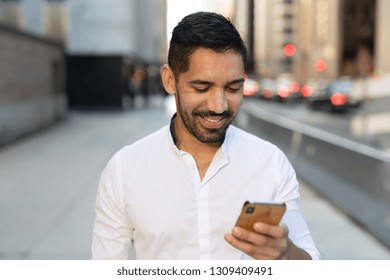 Young Latino Hispanic Man In City Walking Texting Cell Phone