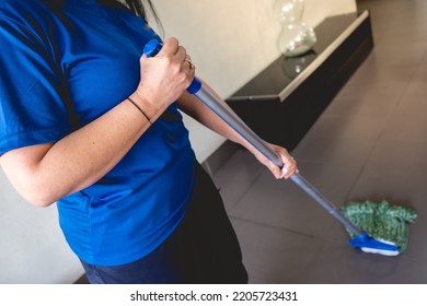 Young Latino Janitorial Worker Lady In Blue Uniform Cleaning In Building With Industrial Vacuum Cleaner