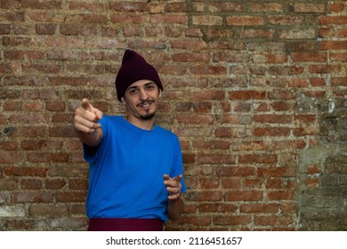 Young Latino Male (28) Points Forward Pointing His Fingers. Copy Space, Brick Background.